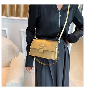 Detail showing high-shine gold leather crossbody bag with metallic square buckle