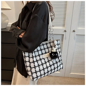 Macro shot of checkered wool tote bag with a leather patch and plush monster pendant