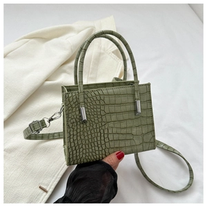 Detail of green crocodile texture pattern on stylish tote bag with silver hardware
