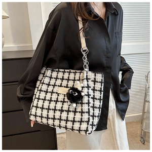 Detail of black and white tweed tote bag with plush monster charm and chain strap
