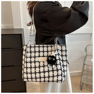 Detail of tweed checkered tote bag with chain strap and cute black plush charm