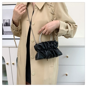 Detail of black pleated crossbody bag with rhinestone handle and silver chain strap