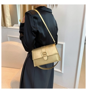 Close-up of golden rectangular crossbody bag with matte metallic finish on black silk