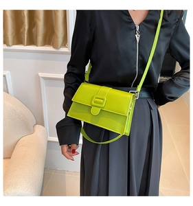 Lime green patent leather crossbody bag shown on a model with a black satin shirt