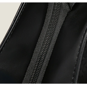 Gros plan sur la texture du cuir noir mat et la fermeture éclair d'un grand sac