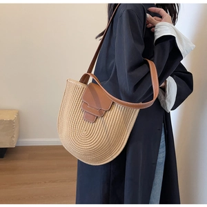 Detail of woven straw shoulder bag with brown leather flap and contrast stitching