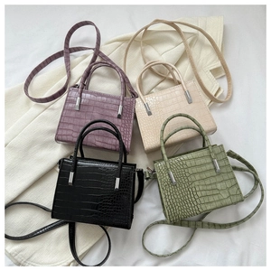 Close-up of four colorful crocodile pattern PU leather tote bags on white fabric
