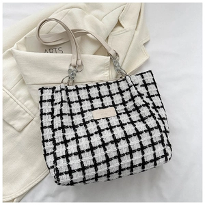 Detail of black and white plaid tote bag with silver chain and leather strap