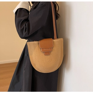 Close-up of hand-woven bucket bag with brown leather flap and white contrast stitching