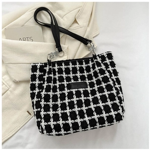 Detail of black and white tweed tote bag with leather strap and silver chain accents