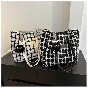 Detail of tweed bucket tote bags in black and white plaid with plush charm pendants