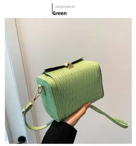 Dettaglio borsa a tracolla verde con trama a onde e chiusura a girello dorata