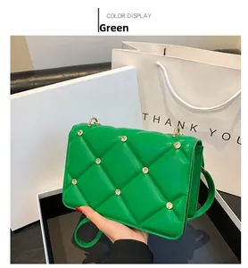 Detail view of green quilted leather bag with studs and matching long shoulder strap