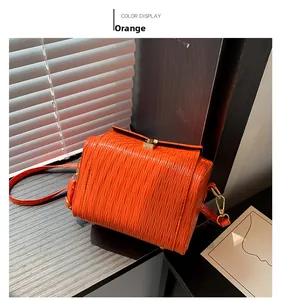 Dettaglio della borsa box arancione vivace con texture a onde e dettagli in metallo oro