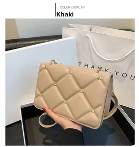Detail of khaki quilted crossbody bag with gold rivet accents and elegant chain strap