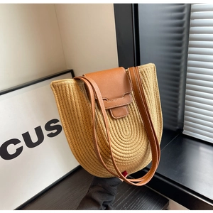 Detail of woven straw tote bag with brown leather straps and contrast stitching
