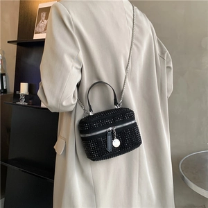 Elegant black rhinestone crossbody bag with silver chain worn by a woman in a suit