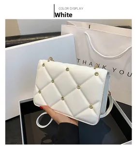 Detail of white quilted bag with rhinestone studs and gold hardware in hand