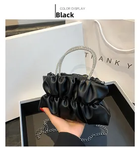 Detail of black pleated cloud bag featuring sparkling rhinestone handle and silver chain strap