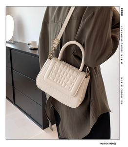 Detail van de gebroken witte gewatteerde handtas met krokostructuur en goud