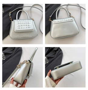 Detailweergave van de zilveren handtas met krokodillenpatroon en metalen handvat