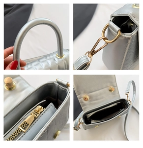 Detailweergaven van de zilveren gewatteerde crossbodytas met gouden hardware en rits