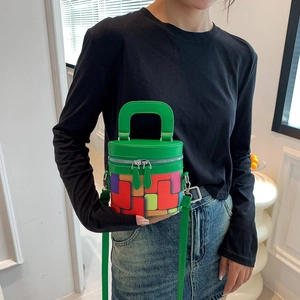 Green cylindrical bucket bag with colorful geometric patterns and adjustable strap
