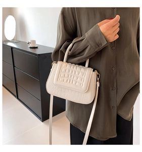 Detail van beige crossbodytas met gewatteerde klep en vintage krokodillenleer textuur