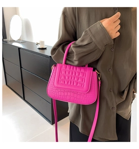 Detail van fuchsia handtas met krokodillenreliëf, gewatteerde flap en gouden accenten