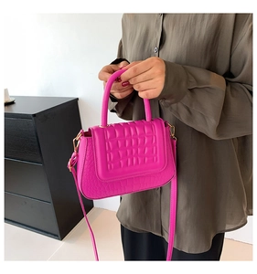Detail van fuchsia kunstlederen tas met krokodillenstructuur en gouden hardware