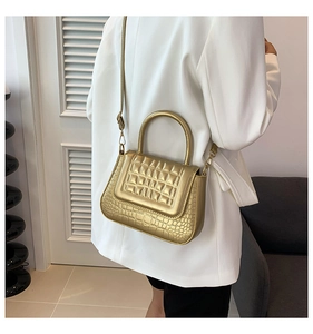 Gouden handtas met krokodillenreliëf en stikselpatroon bij een witte blazer outfit