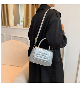 Detail van zilveren gewatteerde crossbodytas met krokodillenprint en goud beslag