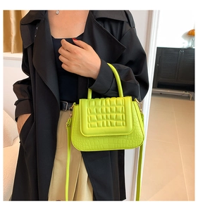 Detail van neongroene handtas met krokodillentextuur, gewatteerde flap en gouden gespen