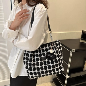 Fashionable black and white checkered tweed bucket bag with plush charm and chain strap