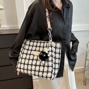 Chic black and white tweed bucket bag with plush monster charm and chain strap