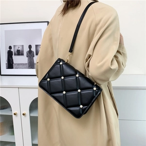 Elegant black quilted crossbody bag with diamond studs, styled on a beige trench coat