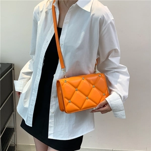 Quilted orange crossbody bag with metal rivets shown on a model for casual styling