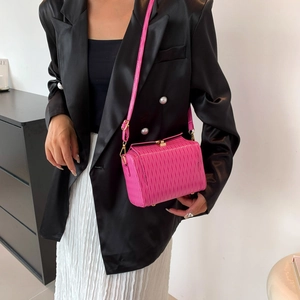 Sac cylindre en cuir verni plissé rose avec chaîne porté par un mannequin