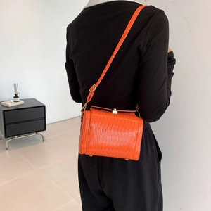 Sac à bandoulière orange vif avec texture ondulée et détails en métal doré élégants