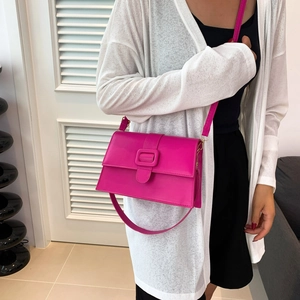 Minimalist fuchsia patent leather square crossbody bag with handle shown on model