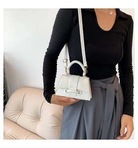 Detail of a white crossbody bag with lychee texture and elegant gold hardware