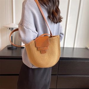 Minimalist woven bucket bag with leather flap shown on model in indoor setting