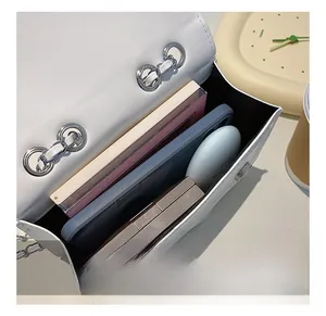 Detailed internal view showing capacity of white lychee leather chain bag with items