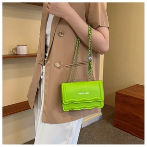 Détail du sac à chaîne vert néon avec rabat ondulé et inscription FASHION & BAG