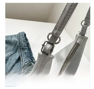 Detail of adjustable silver buckle and stitching on grey soft PU leather shoulder bag
