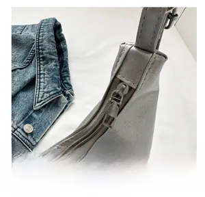 Detail of smooth silver metal zipper on grey PU leather versatile shoulder bag