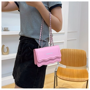 Detailed view of pink shoulder bag featuring wavy pleated edges and a silver chain strap