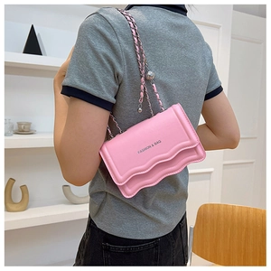 Détail du sac à chaîne rose avec bord ondulé présenté dans une scène d'intérieur