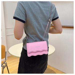 Détail du sac à bandoulière rose à bords ondulés avec lettrage et chaîne dorée