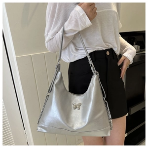 Close-up of metallic silver crescent hobo bag with butterfly logo and chain detail